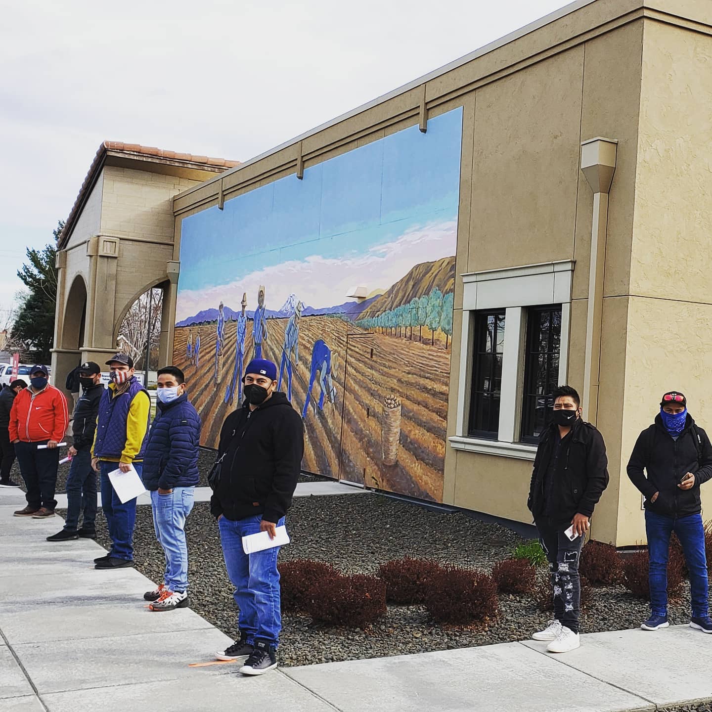 People lined up outside, wearing masks, waiting for COVID-19 vaccines.